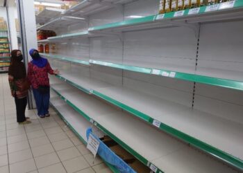 ROZIDAH Amat (kanan) bersama ibunya melihat rak minyak yang kosong di sebuah pasar raya di Johor Bahru.