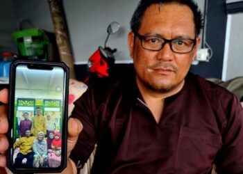 SEORANG lagi bapa saudara mangsa, Mohd. Borhan Paralan menunjukkan gambar anak saudaranya, Allahyarham Iqbal Hasnun Halimi (berdiri kiri) bersama ahli keluarganya ketika menyambut hari raya di Benut Pontian baru-baru ini ketika ditemui di Taman Impian Jaya, Senai di Johor Bahru. -UTUSAN/RAJA JAAFAR ALI
