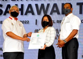 NOH Omar (kiri) menyerahkan nota perlindungan Perkeso kepada usahawan Tekun Nasional, Selvi Narayanasamy sambil diperhatikan M. Saravanan sempena Majlis Pelancaran Kempen Mencarum Perkeso Usahawan Tekun di Hotel Renaissance, Johor Bahru. -UTUSAN/RAJA JAAFAR ALI