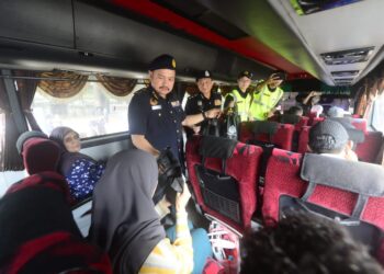 KAMARUL ISKANDAR Nordin (depan) menyampaikan cenderahati kepada penumpang bas ekspres pada Operasi Penguatkuasaan Perayaan Sempena Tahun Baharu Cina 2023 di Terminal Sentral Kuantan (TSK) di Kuantan, Pahang. - FOTO/SHAIKH AHMAD RAZIF