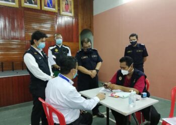 AZMIL Zainal Adnan (berdiri, dua dari kanan) melihat kompaun yang dikeluarkan anggotanya kepada salah seorang pengusaha syarikat bas kilang di JPJ Cawangan Muar, Johor. -UTUSAN/NUR ALINA HASSAN