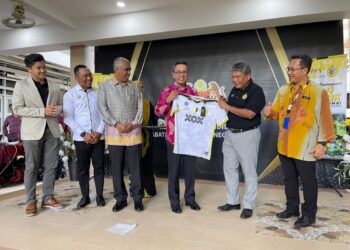 ABDUL Azim Mohd. Zabidi (dua kanan) menyerahkan jersi Perak FC kepada Mohamad Fauzi Mahson  pada majlis menandatangani kerjasama program pembangunan bola sepak akar umbi negeri Perak di Ipoh hari ini. - UTUSAN