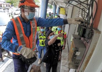NORZAINY Mohd. Noor melihat petugas TNB memotong bekalan elektrik sebuah premis  perniagaan loteri haram di Butterworth, semalam. – UTUSAN/AMIR IRSYAD OMAR