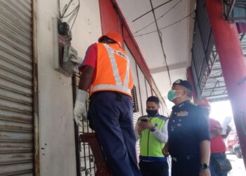 OSMAN Mamat (kanan) melihat kakitangan TNB memotong bekalan elektrik di premis yang terlibat perjudian atas talian di Kamunting, Taiping, Perak, hari ini. - FOTO/WAT KAMAL ABAS