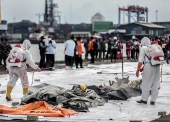 PETUGAS kesihatan menyembur cecair pembasmi kuman ke atas beg mayat yang mengandungi cebisan daging penumpang pesawat Sriwijaya Air. - AFP