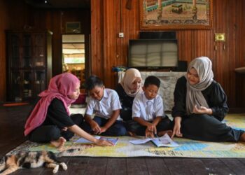 RUTIN Kasih Nurani Zulkepeli (kanan) bersama-sama membantu adik-adiknya menyiapkan kerja sekolah di Kampung Durian Burung di Kuala Terengganu, hari ini. - PUQTRA HAIRRY ROSLI