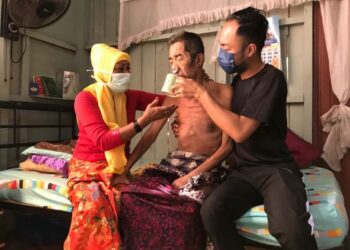 MAKALSOM Ismail bersama anaknya membantu Wan Azman Wan Mohamad minum air bagi mengalas perut di rumah mereka di Kampung Kuala Besar, Kota Bharu semalam. - UTUSAN/ROSLIZA MOHAMED