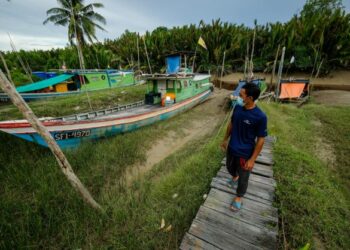 SEORANG nelayan melihat botnya yang tersadai akibat air surut di Sungai Tebelut di Kampung Tengah Tebelut, Kuching,
Sarawak. - UTUSAN/MUHAMAD IQBAL ROSLI