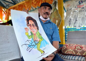 TAZIDI Yusuf menunjukkan karikatur eksklusif Datuk M. Daud Kilau yang akan dijual dan hasilnya disumbangkan kepada penyanyi veteran itu. – Utusan/ZULFACHRI ZULKIFLI
