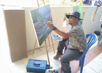 ALIZAN Alias membuat catan bertemakan jeram Sungai Tembeling ketika membuat pameran dan jualan di Kuala Tahan, Jerantut, Pahang baru-baru ini. 
– utusan/HARIS FADILAH AHMAD