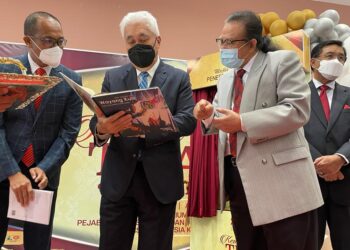 TENGKU Mohamad Rizam membelek buku Wayang Kulit hasil tulisan Lim Swee Tin (kiri) dalam Majlis Kembara Titah Kelantan di UMK Bachok, Kelantan. - UTUSAN/TOREK SULON