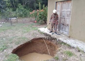 SEORANG anggota bomba memantau lubang besar seperti di hadapan pintu rumah Zaili Abu Bakar di Kampung Berchang Baru, Kuala Lipis di Lipis, Pahang.