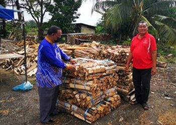 JUMALI Supar (kanan) bergambar bersama Abdul Razak di samping kayu api yang akan dihantar kepada pelanggan di rumahnya di Kampung Kebun Baru hari ini. - UTUSAN / ABDUL RAZAK IDRIS
