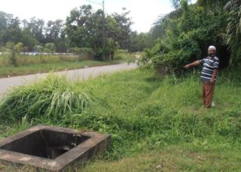 SEORANG penduduk menunjukkan longkang yang tidak diselenggara sehingga dipenuhi rumput di jalan pintas antara Taman Semarak dan Padang Temusu, Sungai Petani, Kedah. - UTUSAN/OTHMAN YAHAYA