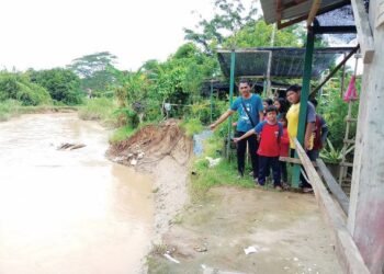 ZAMRI Ahmad (kiri) dan beberapa kanak-kanak menunjukkan tebing sungai yang runtuh akibat hakisan banjir di Taman Mesra Ria, Kupang di Baling, Kedah. - UTUSAN/NORLIA RAMLI