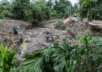 SEORANG penduduk melihat keadaan jambatan yang masih dalam pembinaan musnah selepas dilanda banjir kilat di Kampung Teluk Sanau, Batu 7, Baling, Kedah. - UTUSAN/ SHAHIR NOORDIN
