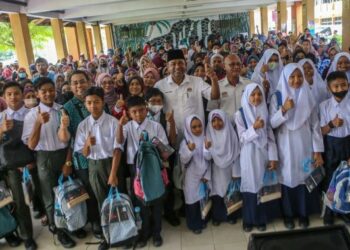 ABDUL Azeez Rahim (tengah) bersama pelajar-pelajar yang terjejas banjir dalam Program Agihan Set Seragam Bagi Murid Terkesan Banjir Daerah Baling di SMK Jerai, Kupang, Kedah, hari ini.- FOTO/SHAHIR NOORDIN