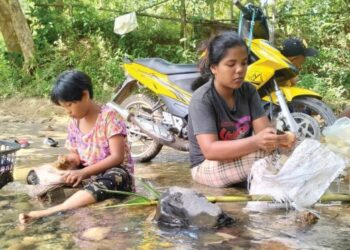 SITI Solehah Hiddayah Rani membasuh rebung manakala anak saudaranya, Siti Zulaikha Mohd. Ridzuan, 12, mencuci pakaian di sungai dekat Kampung Wang Perah, Jitra, Kubang Pasu, Kedah. – FOTO/MOHD. RAFIE AZIMI