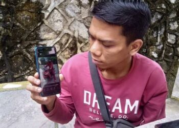 MOHAMAD Najeb Hakim Roslan menunjukkan gambar arwah adiknya ketika ditemui di Unit Forensik HSAH, Sungai Petani, Kedah. - FOTO/OTHMAN YAHAYA