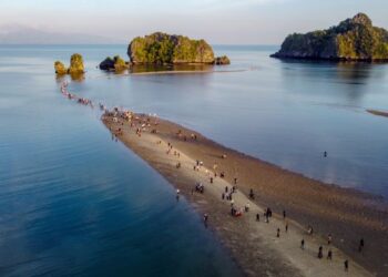 SEBAHAGIAN pengunjung berjalan kaki di beting pasir sehingga 'laut terbelah' ketika fenomena air surut penuh di Pantai Tanjung Rhu, Langkawi, Kedah.- UTUSAN/SHAHIR NOORDIN