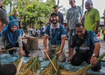 MUKHRIZ Mahathir (tengah) mencuba salah satu teknik memukul padi secara tradisional yang digunakan dalam penghasilan emping ketika hadir ke Program Jom Mengemping di Megat Dewa, Jerlun, Kedah. - FOTO/SHAHIR NOORDIN