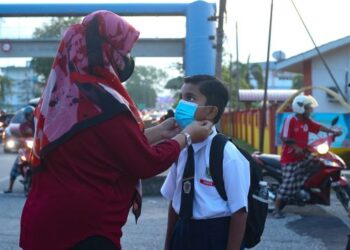 SALWANA Sharudin memakaikan pelitup muka kepada anaknya, Muhammad Syafiq Mohd. Noor, 9, ketika memulakan sesi persekolahan di SK Tunku Abdul Rahman Putra, Kuala Nerang, Padang Terap. – UTUSAN/SHAHIR NOORDIN