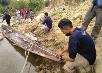 KAKITANGAN Jabatan Warisan Negara melakukan kerja mengukur perahu sagor yang ditemukan penduduk di Sungai Ketil di Kampung Lela, Kuala Pegang, Baling, Kedah. - UTUSAN/NORLIA RAMLI