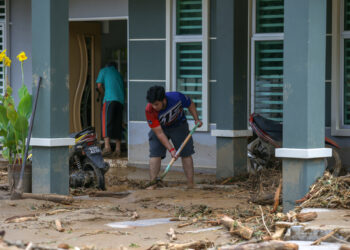 Seorang penduduk membersihkan rumahnya yang terjejas teruk akibat fenomena kepala air di Titi Hayun, Yan, semalam. - UTUSAN/ SHAHIR NOORDIN