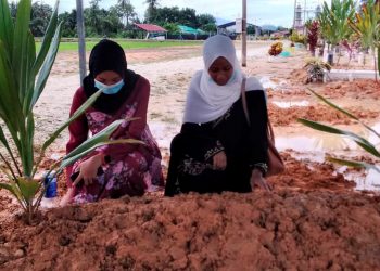 NURUL Shahiera Najwa Mohamad (kanan) bersama rakannya di sisi kubur Nurul Muliani di Tanah Perkuburan Islam Alor Pongsu, Bagan Serai, semalam. – UTUSAN/WAT KAMAL HASAN