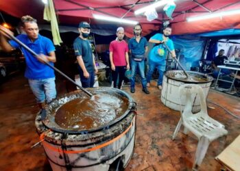 MUHAMAD Azman Ab. Rahim (kanan) bersama pekerja mengacau dodol yang dimasak di bazar Aidilfitri di pekan Kulim, Kedah. - UTUSAN/AZAHAR HASHIM