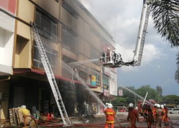 ANGGOTA bomba sedang memadam kebakaran di dua buah kedai hardware di Pekan Wakaf Tapai, Marang, petang tadi. - UTUSAN/NOOR HAYATI MAMAT 