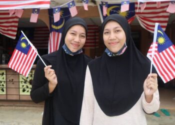 SITI Suzana Sahar (kanan) bersama kembarnya, Siti Suhana Sahar teruja dan sentiasa menantikan bulan Ogos dan September bagi menyambut Hari Kebangsaan dan Hari Malaysia di Felda Jengka 23 di Maran, Pahang. - UTUSAN/SALEHUDIN MAT RASAD