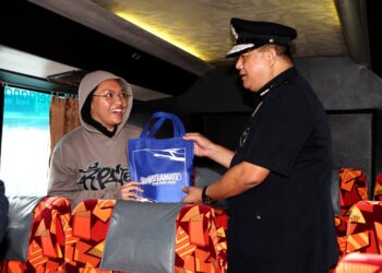 AZIZI Mat Aris (kanan) menyampaikan beg cenderahati kepada penumpang bas pada Kempen Kesedaran dan Keselamatan Jalan Raya Masyarakat Pulang Ke Kampung Sempena Tahun Baru Cina 2023 bersama Perkeso Perak di Terminal Meru Raya, Ipoh hari ini. - UTUSAN/ZULFACHRI ZULKIFLI