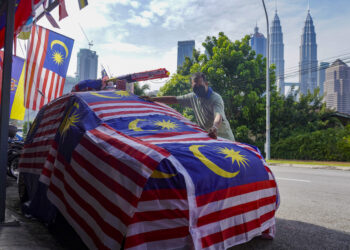 MARZUKI Hanafi, 53, menyiapkan dekorasi 'Kereta Merdeka' sempena bulan kemerdekaan. Lebih 40 helai bendera digunakan dan ia dijadikan sebagai aktiviti tahunan yang dijalankan oleh Pusat Komuniti KRT Kampung Atas A&B Kampung Baru. - UTUSAN/SHIDDIEQIIN ZON