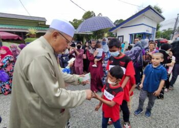 AHMAD Yakob (kiri) memberi duit raya kepada kanak-kanak di Rumah Terbuka Aidilfiri di kediamannya di Kampung Alor Pasir, Tumpat, Kelantan, hari ini. - UTUSAN/YATIMIN ABDULLAH