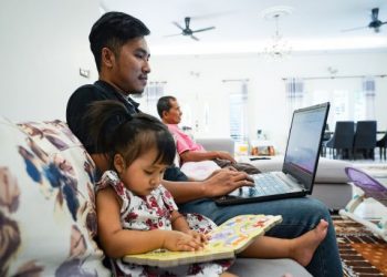 Muhamad Aliffazlan Bahrin melakukan tugasan di komputer ribanya sambil ditemani anaknya, Marissa Irdina di Kampung Bukit Raya, Hulu Langat, semalam.  – UTUSAN/MUHAMAD IQBAL ROSLI