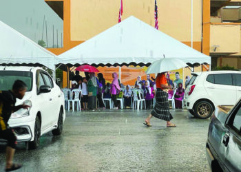 MURID berkumpul di pondok dan khemah khas yang disediakan sebelum dijemput pulang ibu bapa masing-masing di SK Cherang Ruku, Pasir Puteh, Kelantan, semalam. - UTUSAN/TOREK SULONG