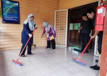 DR. Kasemani Embong (kiri) membantu kakitangan Jabatan Kesihatan Negeri Terengganu membersihkan Klinik Desa Kuala Jengal, Dungun yang dinaiki air, baru-baru ini.