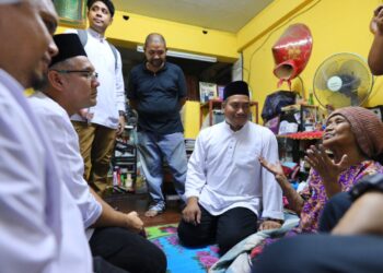 NAZIRUL Jamaluddin (tengah) menyantuni seorang warga emas pada program Singgah Sahur Pemuda UMNO Perak di Ipoh semalam. - UTUSAN