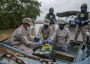 Mohd. Zawawi Abdullah (kiri) menunjukkan sebahagian daun ketum yang dirampas di Kuala Kedah, kelmarin. - UTUSAN/ SHAHIR NOORDIN