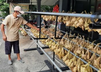 MOHD. YUSRI Mahat melihat ketupat bawang yang sudah dimasak di Kampung Padang, Pokok Mangga, Melaka. - UTUSAN/AMRAN MULUP