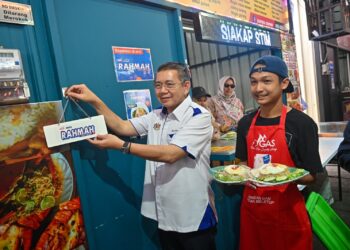 SALAHUDDIN Ayub (kiri) menampal plak Menu Rahmah di sebuah gerai makanan pada Program Jelajah Menu Rahmah dan Penyerahan Bakul Rahmah di sebuah restoran di Wakaf Tok Pelam, Kuala Terengganu, hari ini. - UTUSAN/PUQTRA HAIRRY ROSLI