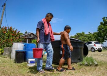 MOHAMAD Harpit Osman dan anaknya, Mohamad Izz berjalan pulang ke rumah selepas selesai mandi menggunakan bekalan air yang dihantar kontraktor SADA di Kampung Jilid 9, Segantang Garam, Merbok, Sungai Petani, Kedah. - UTUSAN/SHAHIR NOORDIN