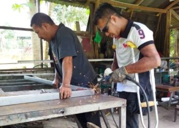 SHAHRUL Nizam Badrulsham (kanan) dan bapanya, Badrulsham Baharom melakukan kerja kimpalan besi ketika berada di bengkel besi miliknya di Kampung Teluk Temelah, Mukim Siong, baru-baru ini