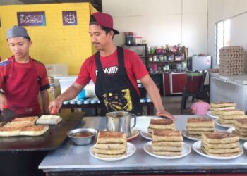 AHMAD Rais Fikri Rosli (kanan) menyiapkan martabak kepada para pelanggan di kedainya di Kampung Kadok, Kota Bharu, Kelantan. - FOTO/ROSMIZAN RESDI