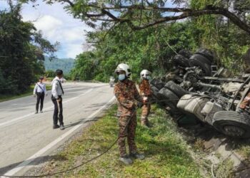 ANGGOTA polis dan bomba berusaha mengeluar mangsa yang tersepit di bawah treler yang terbalik di KM118, Jalan Kota Bharu-Machang-Grik, Batu Melintang, Jeli, Kelantan, hari ini. - FOTO/IHSAN POLIS