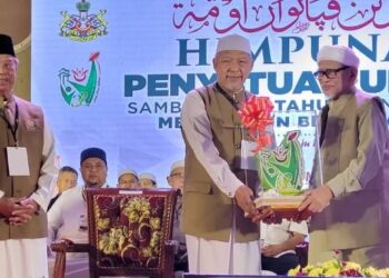MUHYIDDIN Yassin (kiri) melihat Ahmad Yakob menyerahkan pengiktirafan kepada Abdul Hadi Awang (kanan) sebagai Tokoh Penyatuan Ummah pada Himpunan Penyatuan Ummah, Sambutan 32 Tahun Pentadbiran Membangun Bersama Islam di Dataran Warisan, Stadium Muhammad IV, Kota Bharu, Kelantan, malam tadi. - FOTO/MUSTAQIM MOHAMED