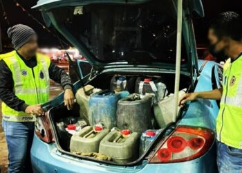 ANGGOTA Penguat Kuasa KPDNHEP Kelantan memeriksa minyak petrol yang dirampas dalam serbuan di Kota Bharu, Kelantan, hari ini. - FOTO/IHSAN KPDNHEP KELANTAN
