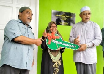 AHMAD Yakob (kanan) menyerahkan replika kunci rumah Dhuafat kepada Rahimah Salleh di Kampung Kutan Tengah, Tumpat, Kelantan. - FOTO/ROHANA ISMAIL