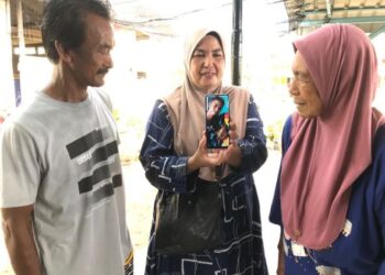 ZAKIAH (tengah) bersama emaknya, Mesah Dollah, 78,, dan abangnya  Ramli, 57, melihat gambar Mohd. Rafi di rumahnya di Kampung Pulau Gajah, Kota Bharu.-FOTO /UTUSAN ROSLIZA MOHAMED